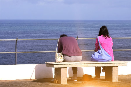 Young couple on a bench near the oceanの写真素材