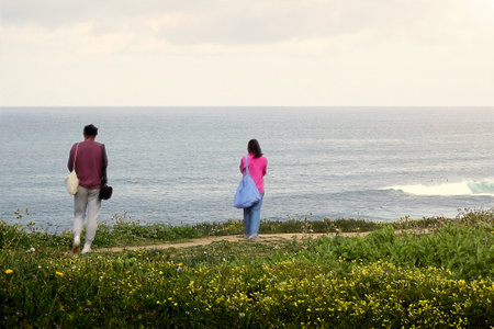 Young couple taking pictures at the ocean on a cloudy dayの写真素材
