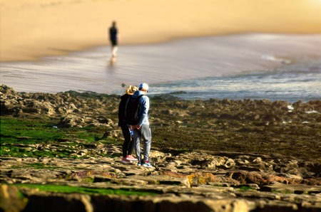 A couple on a rocky beach looking for seashellsの写真素材
