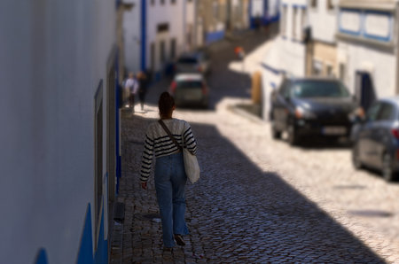 Young woman in jeans walking on a paved streetの写真素材