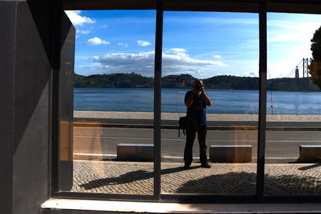 Adult man photographing himself in the reflection of a shop windowの写真素材