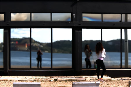 The young woman posing in the reflection of a shop window on the bank of the riverの写真素材