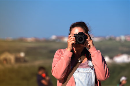 Woman with camera taking pictures on the beach in the evening
