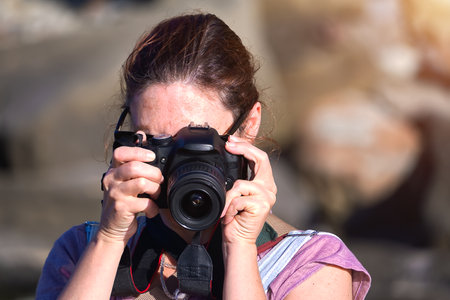 Woman photographing with red hair on the ocean shoreの写真素材