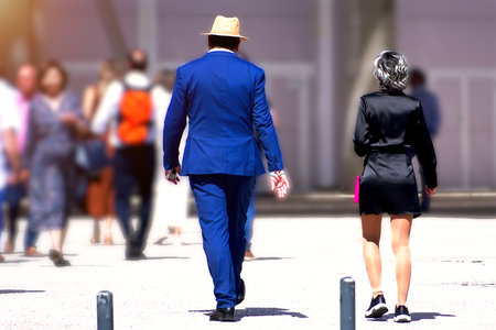 A man in a blue suit with a woman in a black dress walkingの写真素材