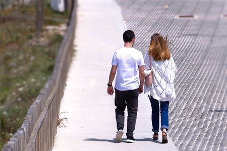 Two lovers holding hands walking down a streetの写真素材