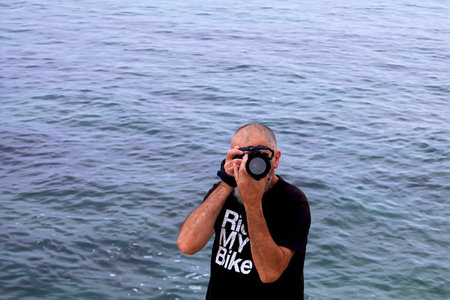 Adult man with camera taking pictures at the oceanの写真素材