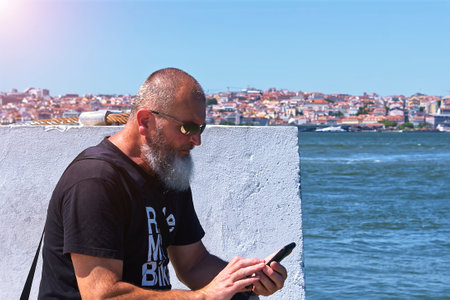 Adult man looking at his phone on the bank of the river