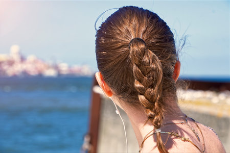 A teenage girl with a braided ponytail looking awayの写真素材