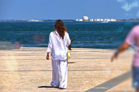 Woman in white walking on the river bankの写真素材