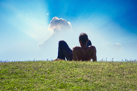 Man standing on the grass looking towards the sunの写真素材