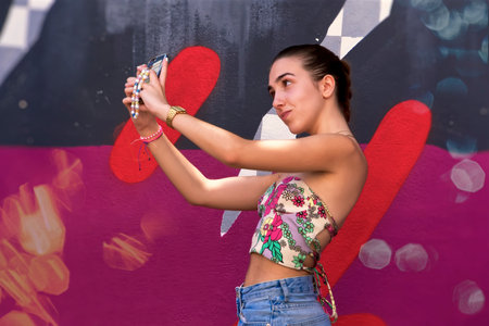 Portrait of a teenager taking pictures next to a wallの写真素材