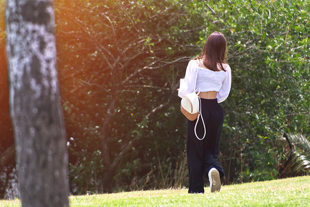 The young woman in a white top walking through the grassの写真素材