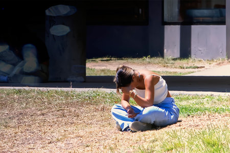 The young woman standing on the grass consulting her cell phoneの写真素材