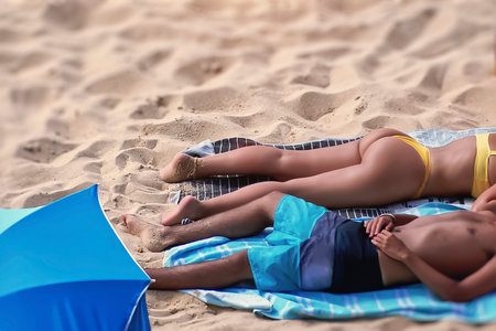A young couple lying on a towel at the beachの写真素材