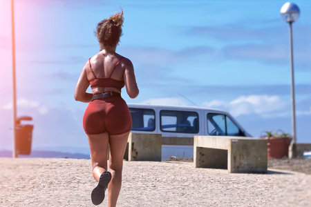 Woman running on the ocean shore on a sunny dayの写真素材
