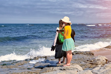 Young tourists on a rocky beach by the oceanの写真素材