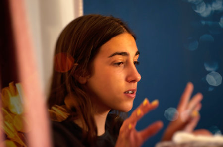 Portrait of a young woman looking through a window at night.の写真素材