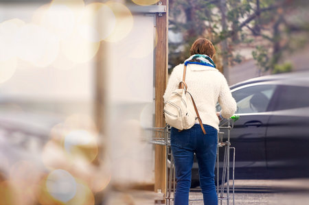 Young woman with shopping cart on the street. Bokeh background.