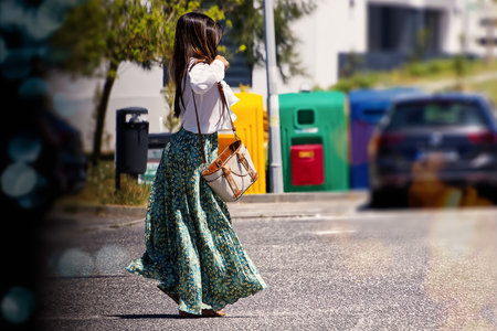 Beautiful woman in a long dress with a bag on the streetの写真素材
