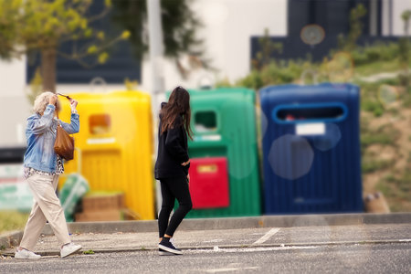 Young woman walking on the street with a trash can in the backgroundの写真素材