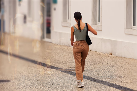 Back view of a young woman walking on the street with backpack.