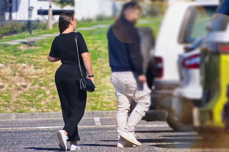 Back view of a woman walking along the road with her boyfriend in the background