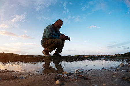 Man with a cam on the beach at sunset. Lifestyle concept.