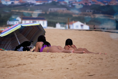 Two girls in bikini sunbathing on the beach. Rear view.の写真素材