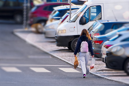 Woman walking on the street with a lot of cars in the backgroundの写真素材