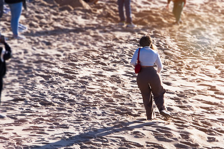 Back view of a woman walking on the beach in the sun.の写真素材