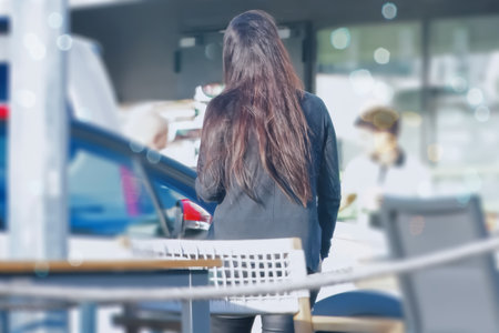 Rear view of a young woman standing in a car dealership.の写真素材