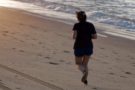Young woman jogging on the beach at sunset. Healthy lifestyle concept.の写真素材