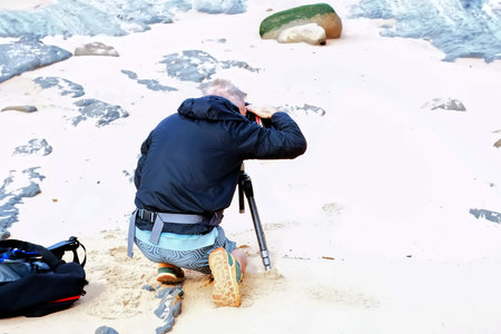 Photographer taking pictures of the seashore with a tripod.の写真素材