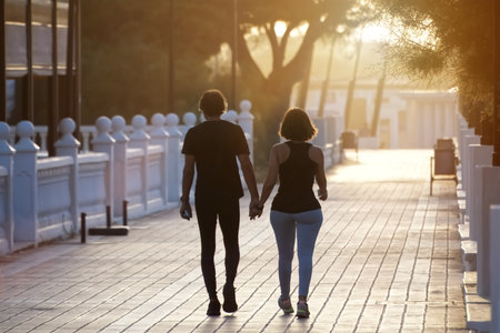 Back view of young couple walking together in the park at sunset.の写真素材