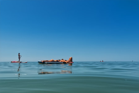A young woman is lying on a surfboard in the sea.の写真素材