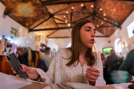 Young woman using mobile phone while sitting at table in a restaurant.