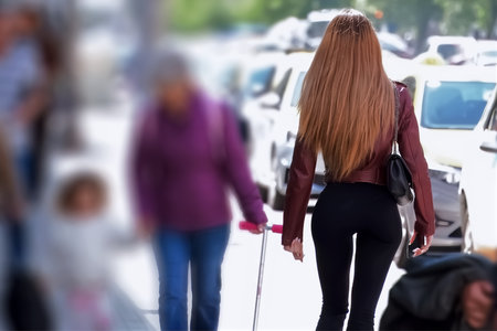 Young blonde woman with long hair walking down the street with a bag on her shoulder