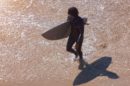 Surfer with his surfboard on the beach in the morning.の写真素材