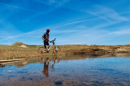 Cyclist Riding Down a Rocky Hillside on a Clear Blue Sky Dayの写真素材