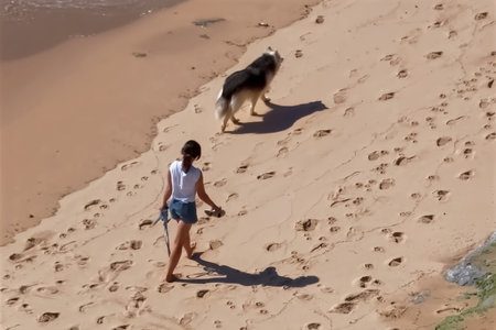 Young woman walking in the sand dunes with her dog on the beachの写真素材