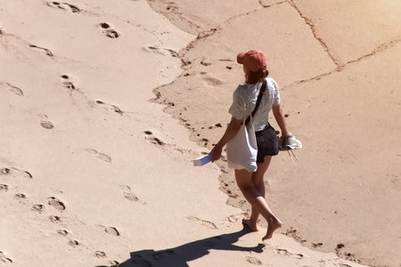 A young woman walking on a sandy beach. Back viewの写真素材