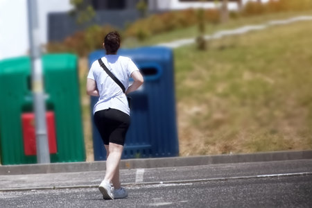 Young person running on city road in early morning, healthy lifestyle conceptの写真素材