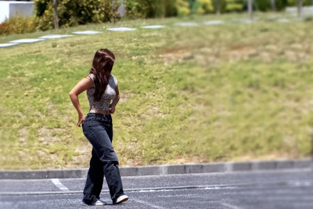 Back view of a young woman walking on the road in the parkの写真素材