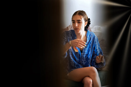 A young woman in a blue bathrobe sits on a chair.の写真素材