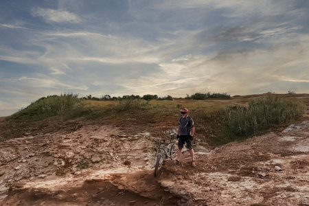 Cyclist standing on the edge of a cliff and looking at the seaの写真素材