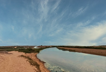 Aerial view of sand dunes and river under blue sky with cloudsの写真素材