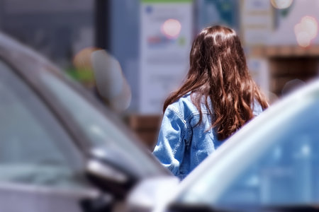 Back view of young woman standing in parking lot, back viewの写真素材