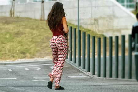 Back view of a young woman walking along the street in the city