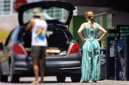 A woman in a long dress stands in front of her car.の写真素材